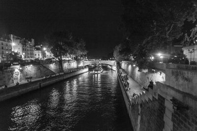 Illuminated bridge over river in city at night