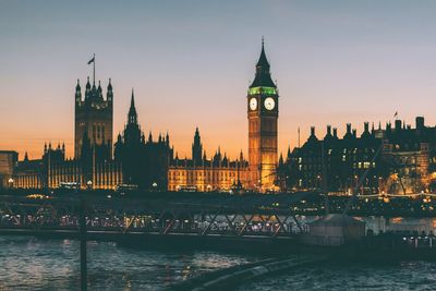 Illuminated big ben and parliament building in front of river thames