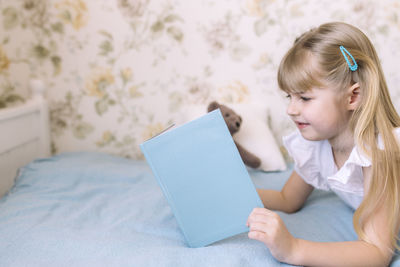 Girl using mobile phone while relaxing on bed at home