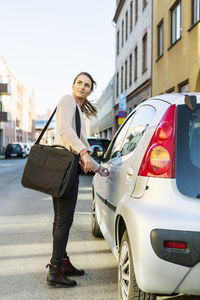 Full length of woman standing on car in city