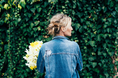 Rear view of woman standing by flowering plants