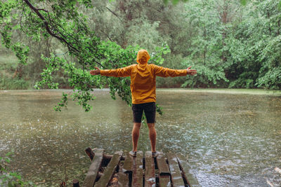 Full length of woman standing by lake during rainy season