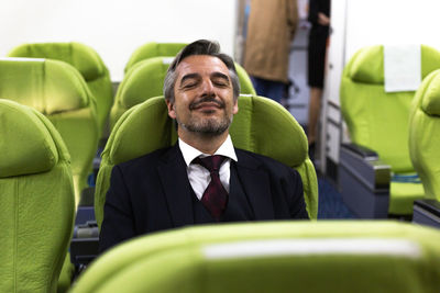 Smiling man with eyes closed sitting in airplane