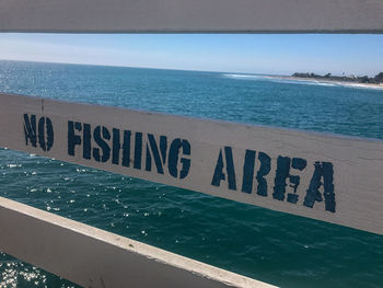 Text on beach against clear blue sky