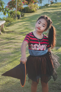 Portrait of girl holding witch hat on field