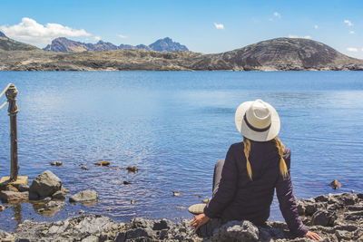 Man standing on rock by lake against mountains