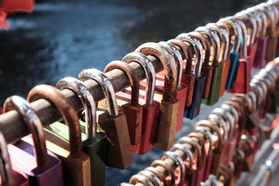 Multi colored padlocks hanging on railing at bridge