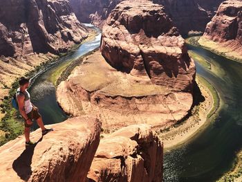 Man standing on rock by river at horseshoe bend