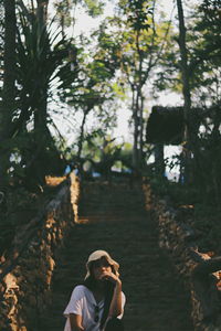 Portrait of woman standing on footpath amidst trees