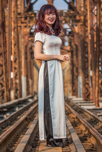 Portrait of a smiling young woman standing on railroad tracks