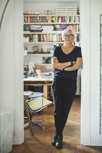 Full length portrait of confident designer standing arms crossed at home