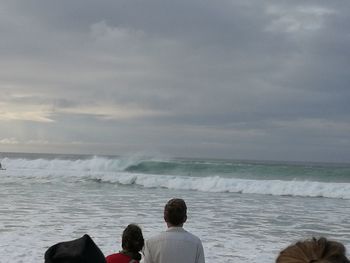 Rear view of people on beach against sky