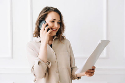 Smiling millennial woman engaged in phone call, discussing documents with client. smiling millennial