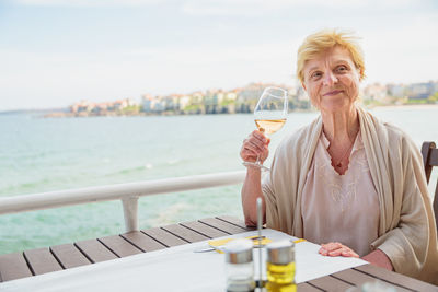 Elderly woman traveler sitting alone on the terrace of coffee shop