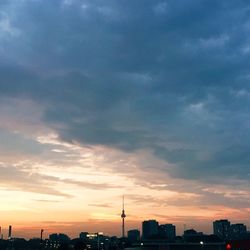 Cityscape against cloudy sky at sunset