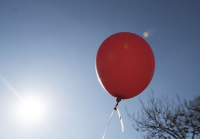 Red balloon and blue sky background with sun, symbol for joy and happiness