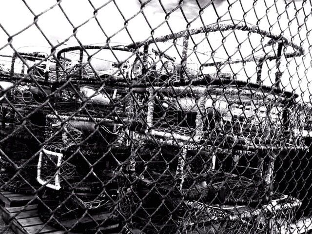 CLOSE-UP OF RUSTY FISHING NET AGAINST BOAT