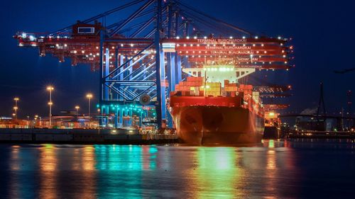 Illuminated commercial dock by river against clear sky at night