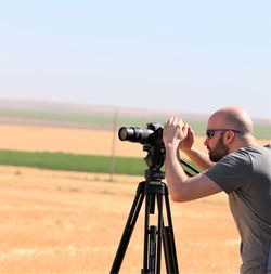 Man photographing on field against clear sky