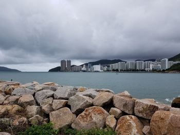 Rocks by sea against sky in city