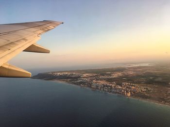 Aerial view of sea and cityscape against sky during sunset