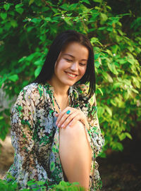 Portrait of smiling young woman standing against plants