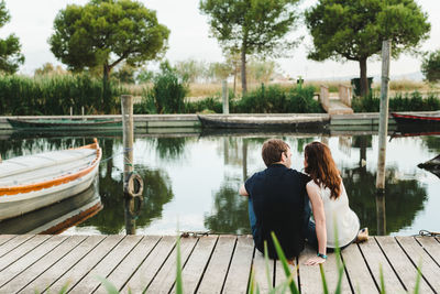 Rear view of couple standing on pier over lake