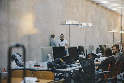 Male and female computer programmers discussing in creative office