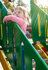Beautiful little girl playing on the playground on a sunny day climbed the wooden stairs