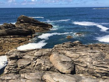 Rocks on shore by sea against sky