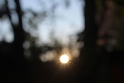 Defocused image of illuminated sun against sky during sunset