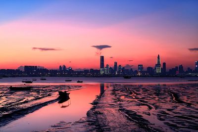 Silhouette of buildings at waterfront during sunset