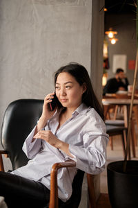Smiling businesswoman talking on phone sitting on chair