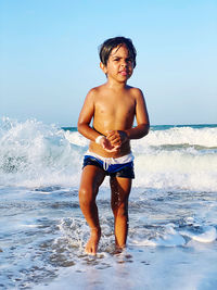 Full length of shirtless boy on beach