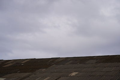Low angle view of house roof and building against sky