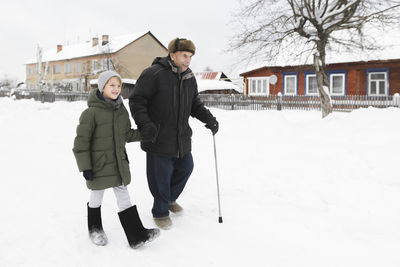 Grandfather and grandson walking together in snow