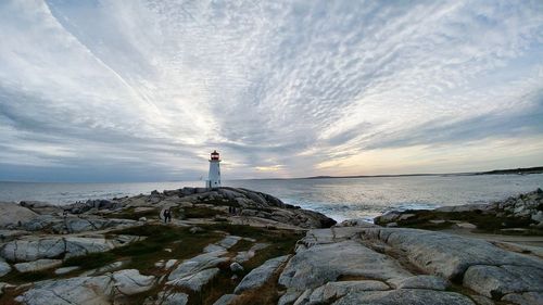 Man standing on rock by sea against sky