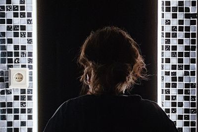 Side view of woman looking through window