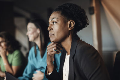 Thoughtful businesswoman with hand on chin during meeting at office