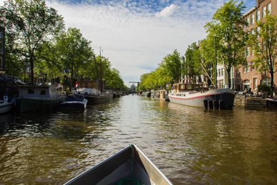 Boats moored on river in city against sky