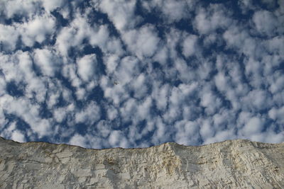 Low angle view of clouds over mountain against sky