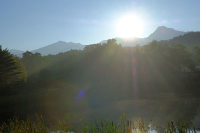 Sunlight streaming through mountains against sky