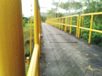 Close-up of yellow railing by empty road