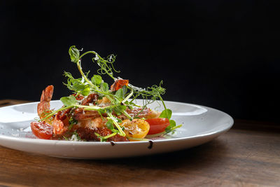 Close-up of salad in plate on table against black background