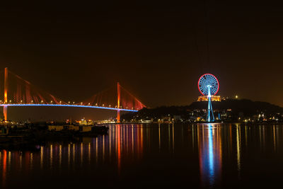 Illuminated bridge over river at night