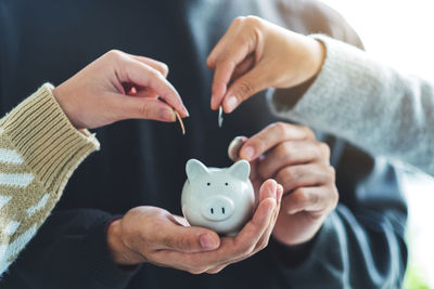 People holding and putting coin into piggy bank for saving money and financial concept