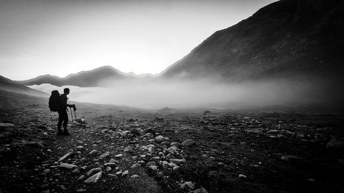 Rear view of man standing on mountain against sky