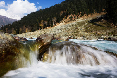 Scenic view of waterfall against sky