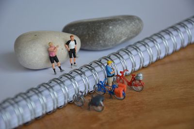 High angle view of figurines with pebbles and spiral book on table