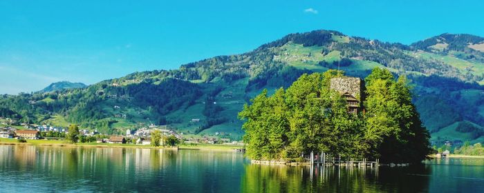 Scenic view of lake and mountains against blue sky